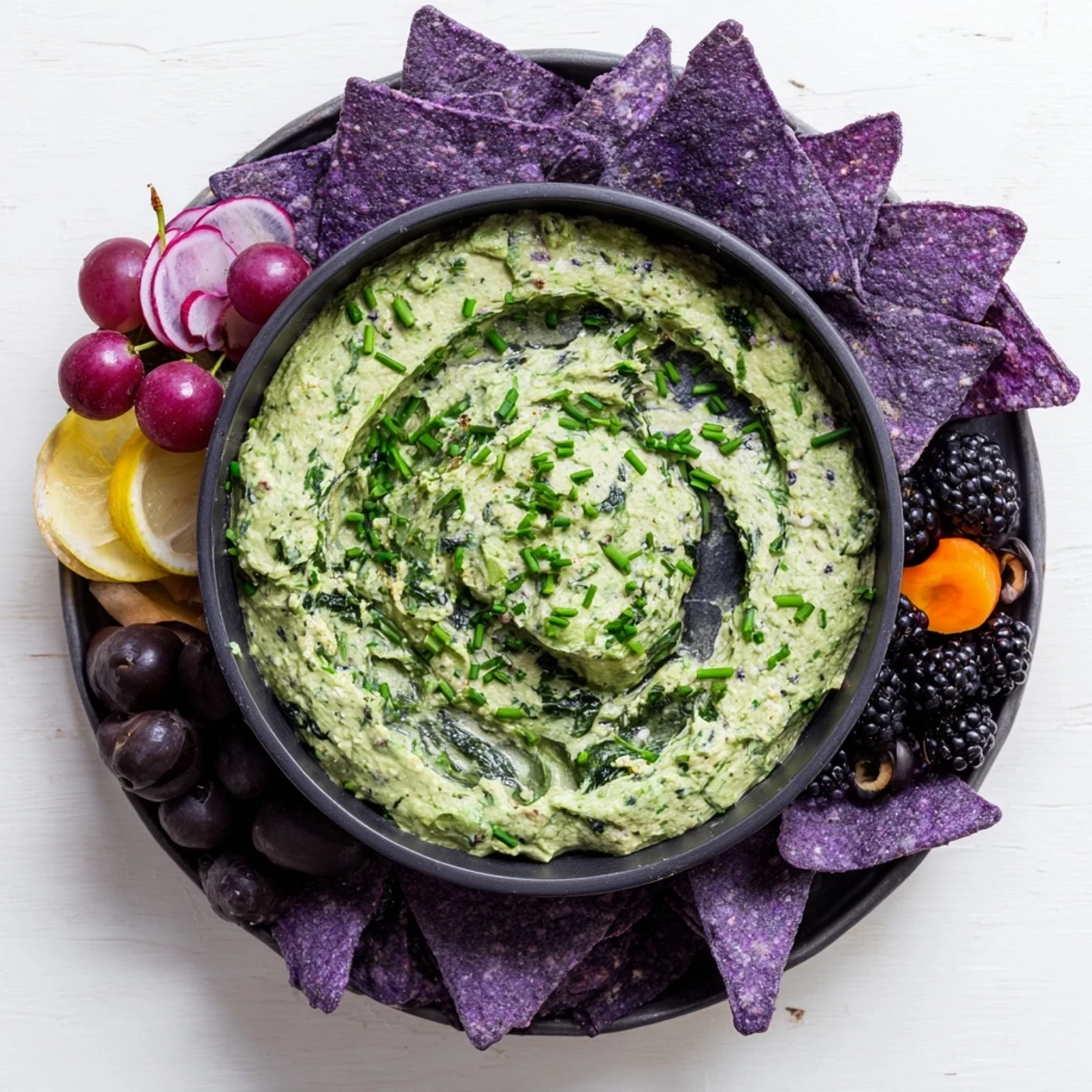 Witch's Brew Cauldron dip, creamy green and bubbling, in a round cauldron surrounded by dark, spooky ingredients.