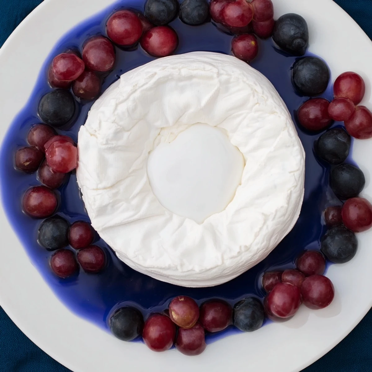 A stunning "Floating Island" appetizer: creamy cheese afloat in vibrant blue yogurt, garnished with grapes.