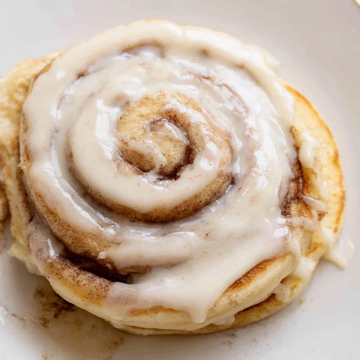 Golden-brown Cinnamon Roll Pancakes are swirled with cinnamon, awaiting a creamy glaze.