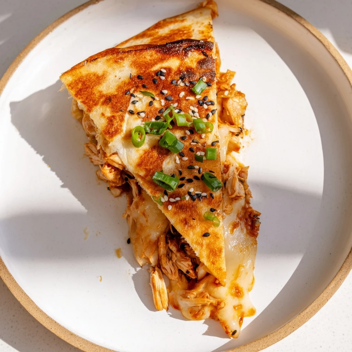 A close-up of a perfectly grilled Korean BBQ Chicken Wrap Grilled Cheese, sesame seeds sprinkled on top.