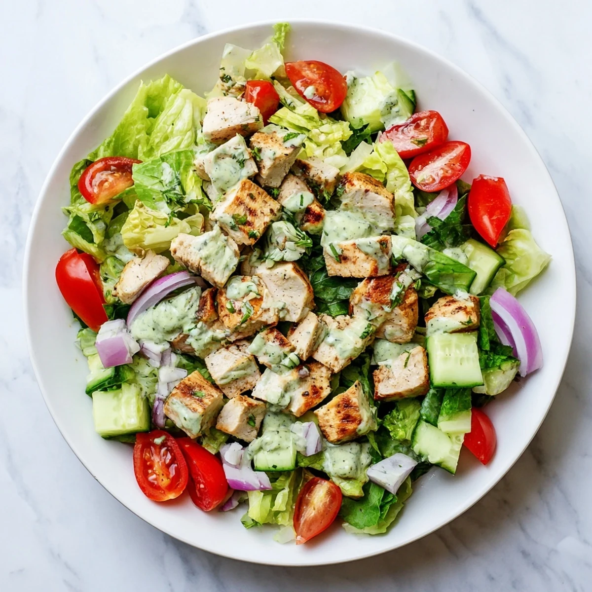 Bright green avocado ranch coats tender chicken breast pieces in a hearty salad bowl with crisp veggies for an easy main dish.  