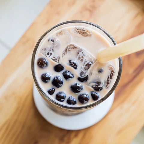 Two glasses of creamy Boba Tea Hack with chewy tapioca pearls and ice, topped with a colorful straw.  