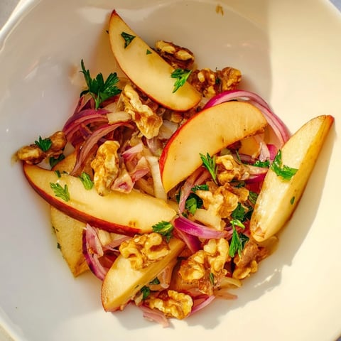 Warm Apple and Sauerkraut Skillet Salad with caramelized apples, red onion, and toasted pecans on a rustic wooden platter.  