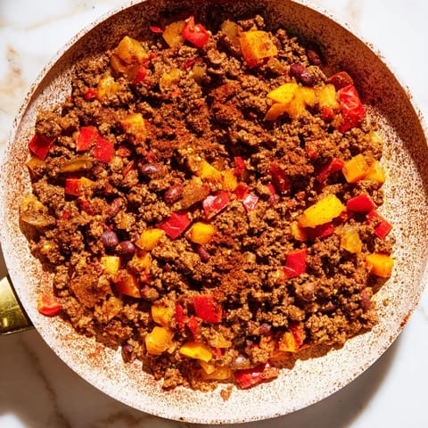 A close-up of a bowl filled with One-Pot Cozy Chocolate Chili, ready to be topped with fresh cilantro.