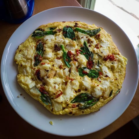 A pan-baked Meadow-Soft Cozy Plate: Frittata with vibrant greens and goat cheese, ready to eat.