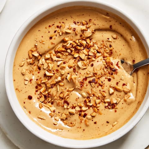 Close-up of bubbling Indonesian satay sauce, a rich peanutty dip with visible spices and aroma.