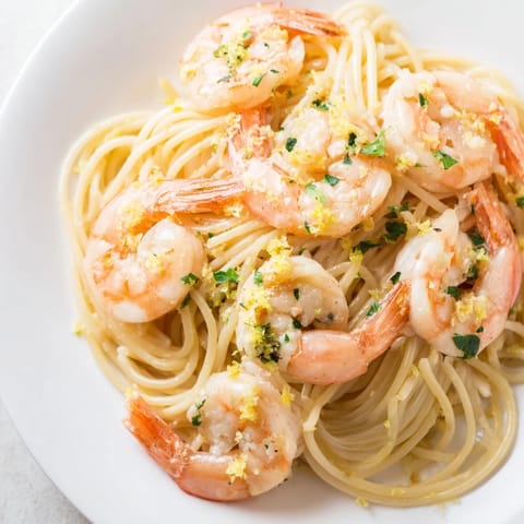 A vibrant serving of Lemon Garlic Shrimp Pasta on a white plate, garnished with fresh parsley and a wedge of lemon. 
