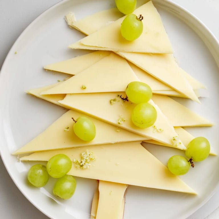 This festive Tannenbaum Border showcases cheese triangles and green grapes, a delicious appetizer ready to serve.
