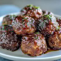 Golden Slow Cooker Peach Glazed Meatballs simmer in a sticky, sweet and tangy sauce, served bubbling with toothpicks for easy party sharing.