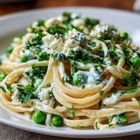 Bright spring pasta with ricotta and lemon linguine, garnished with peas and fresh parsley for a vibrant vegetarian main dish.