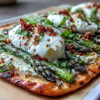 Roasted asparagus flatbread with burrata and lemon, topped with fresh basil and chili flakes for a vibrant spring appetizer.