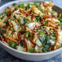 Spicy Cabbage Stir Fry with vibrant green cabbage, crisp carrots, and chili slices sizzling in a hot wok for a quick, healthy meal.